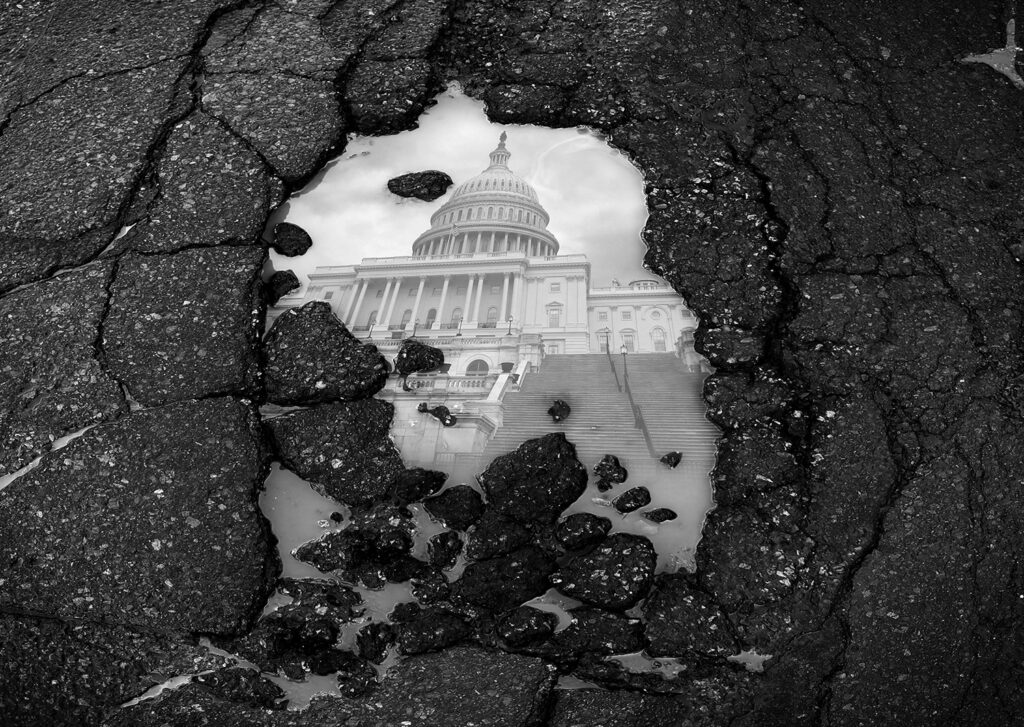 broken asphalt with puddle showing a reflection of White House