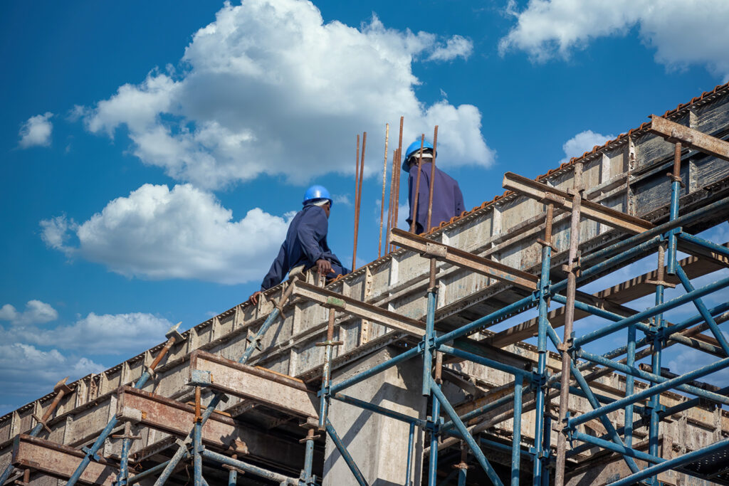 two workers on top of building frame in developing communities