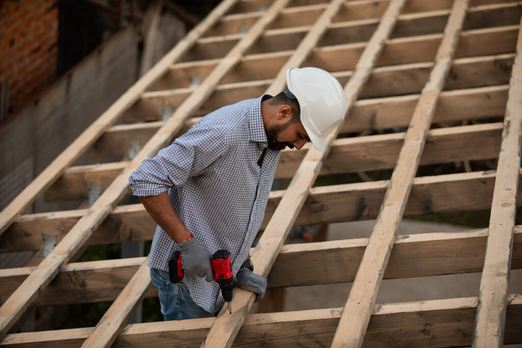 construction worker building frame of roof in developing communities
