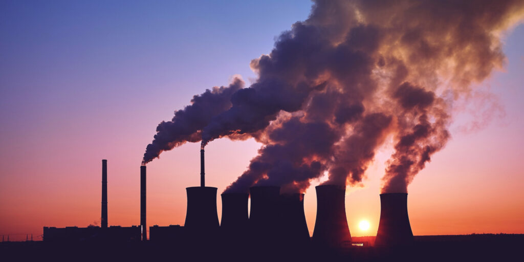 smoke stacks at sunset producing carbon emissions