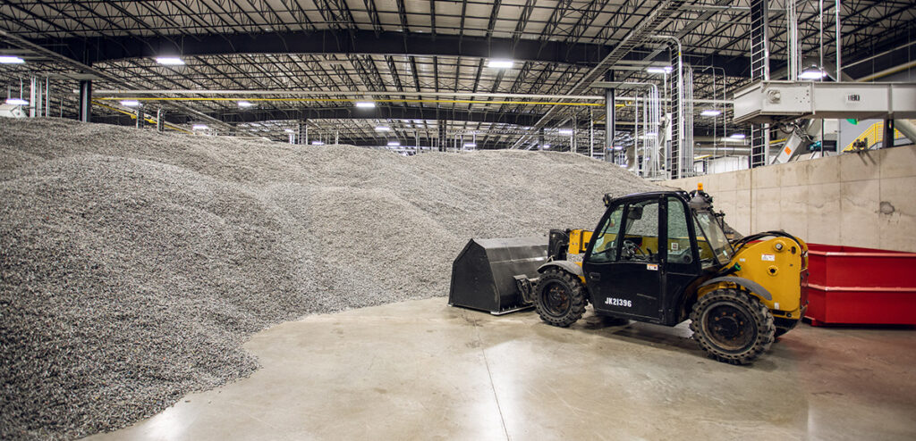 brightmark facility interior showing construction machine and piles of recycled pellets