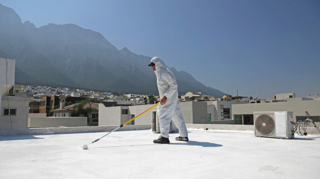 man painting a commercial roof top white as part of a Cool Roadways Partnership initiative
