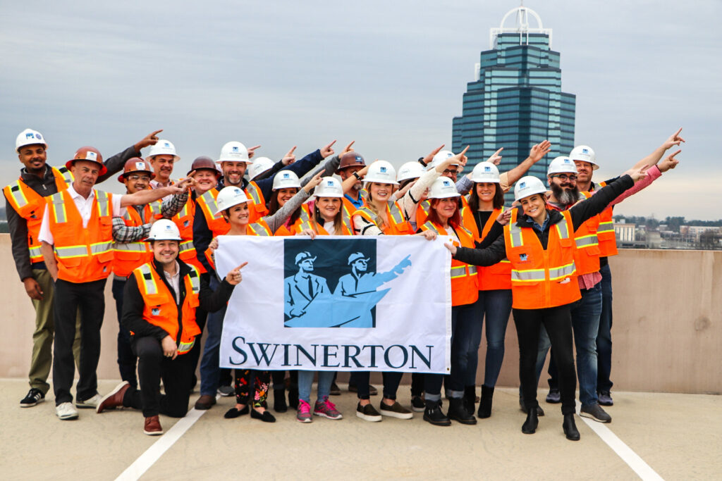 swinerton employees holding logo sign