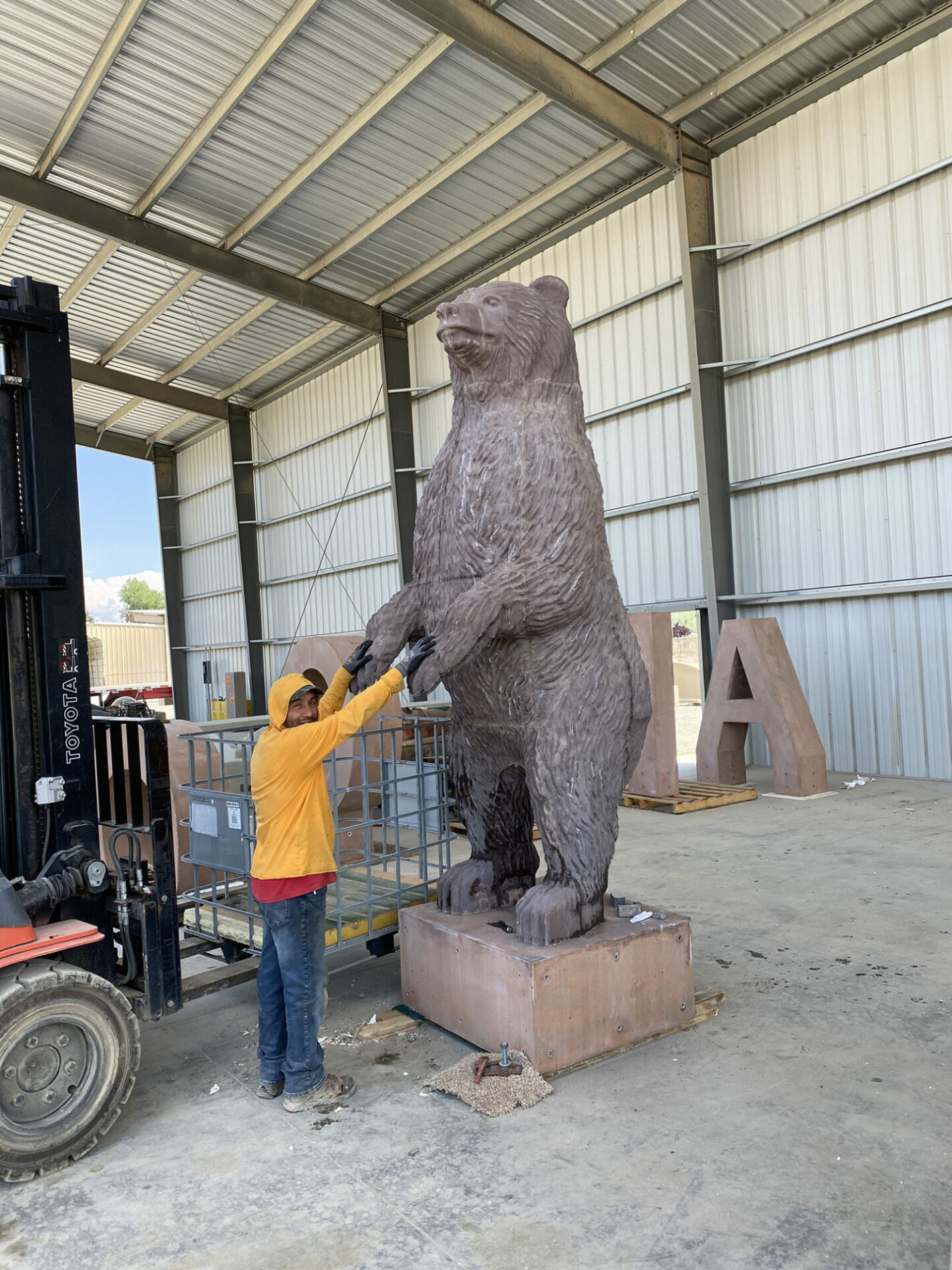 Precast Unlimited worker standing next to concrete bear
