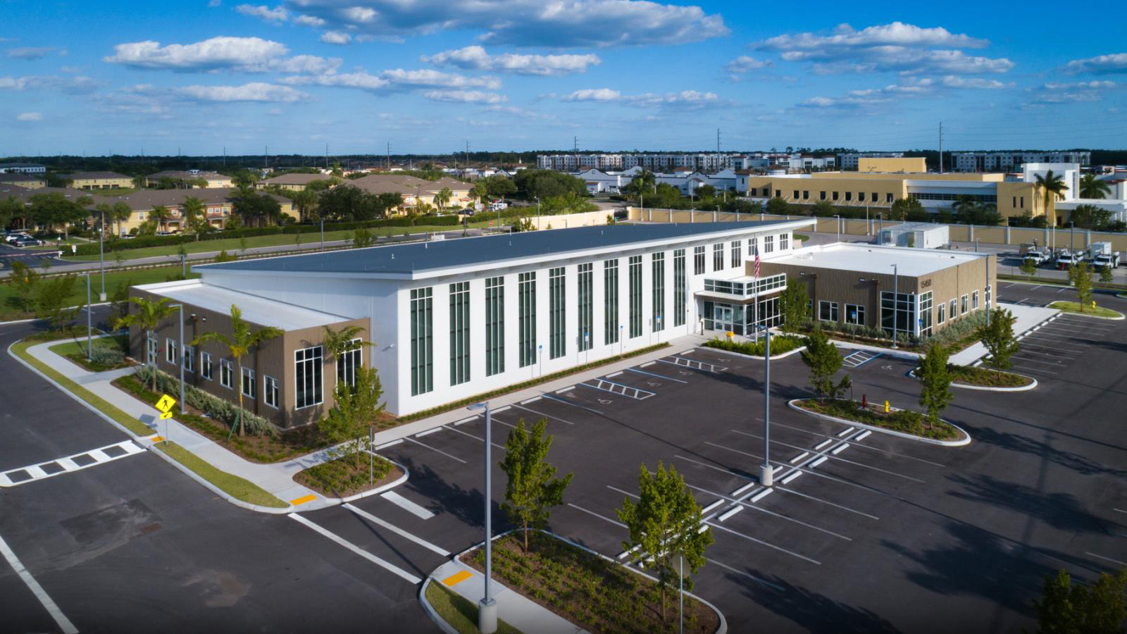 An aerial photo of a building and a parking lot with blue skies.