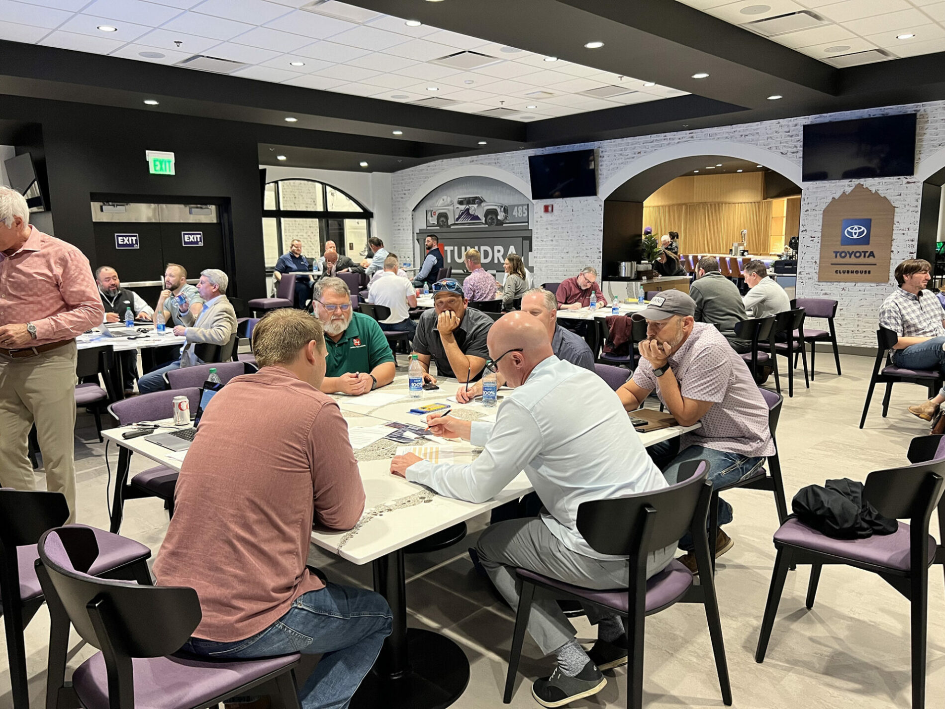 Groups of people sitting at conference tables working in teams and writing.