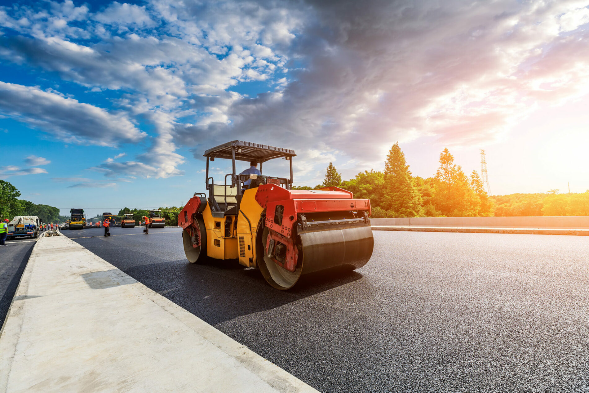 Construction site is laying new asphalt pavement, road construction workers and road construction machinery scene. Highway construction site scene.