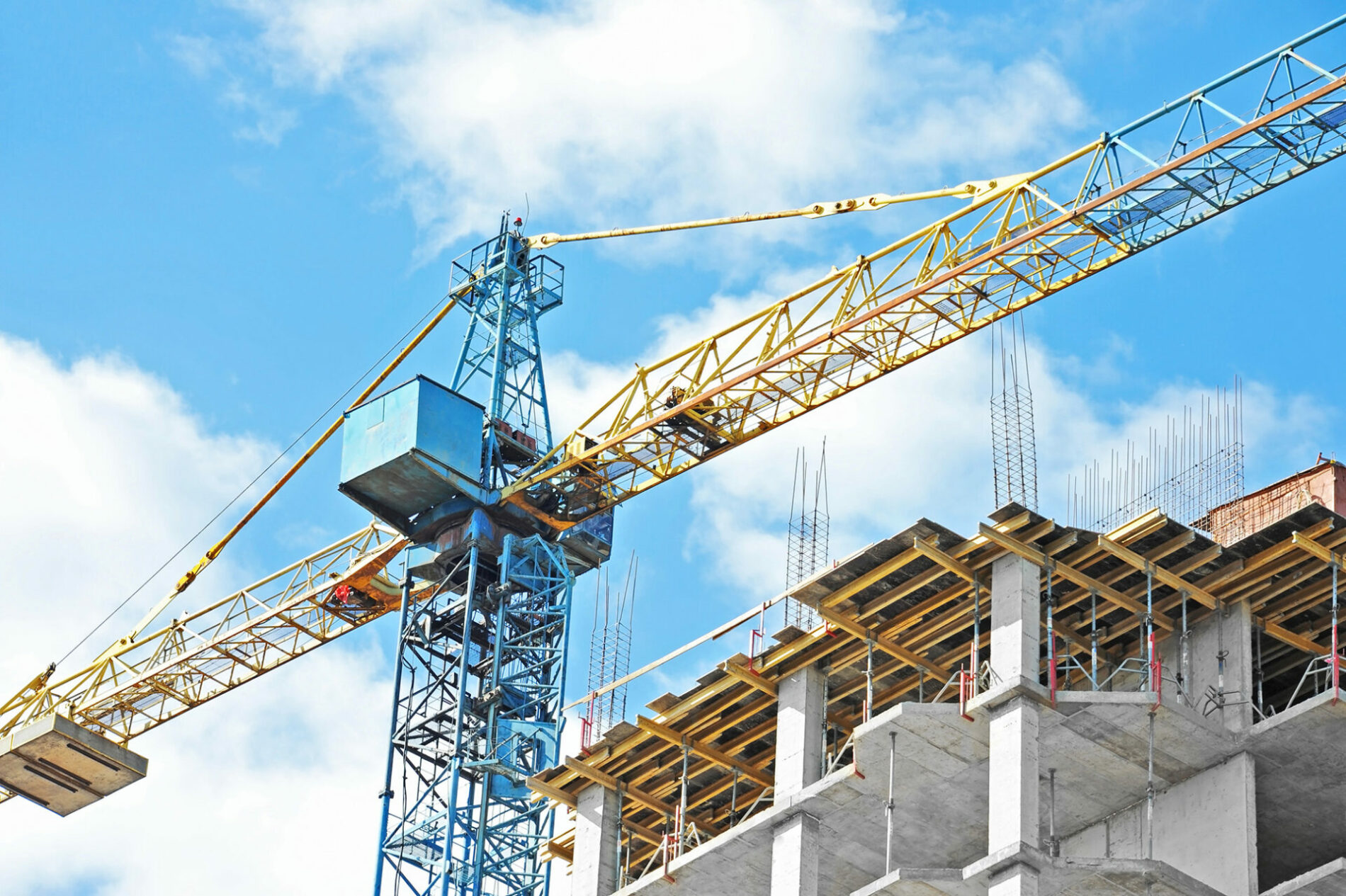 Building crane and building under construction against blue sky