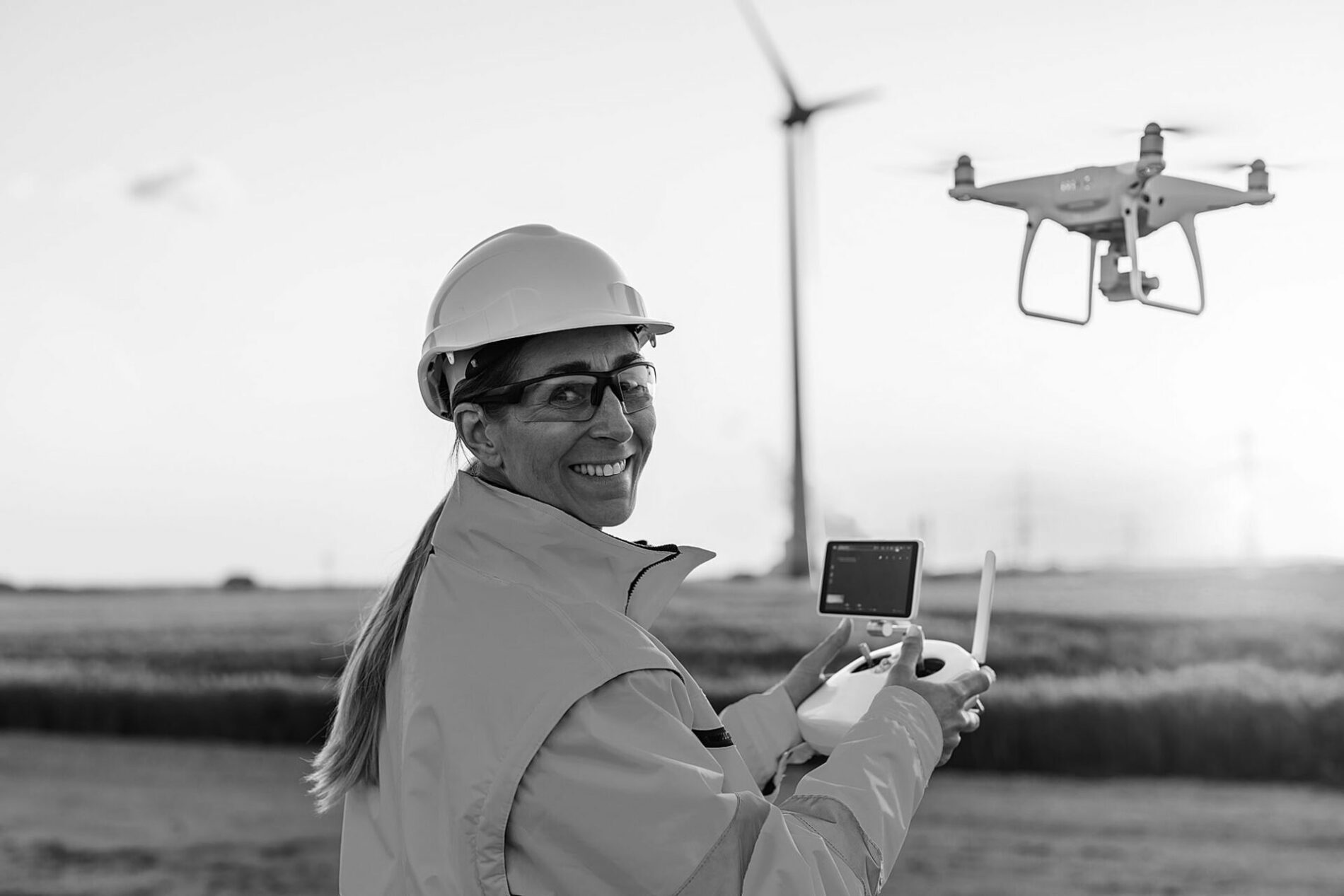 Happy Female Operator inspecting Wind turbine with drone at sunset. Drone inspection concept image. renewable energy wind park in europe