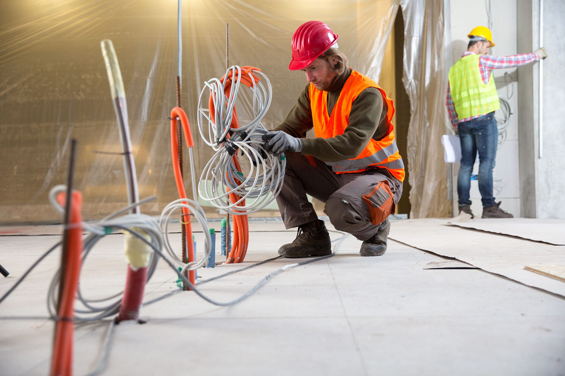 Portrait of a worker, constructing and checking development of a small business hall. Reliable civil engineer working on a construction site, foreman at work, another man in the background