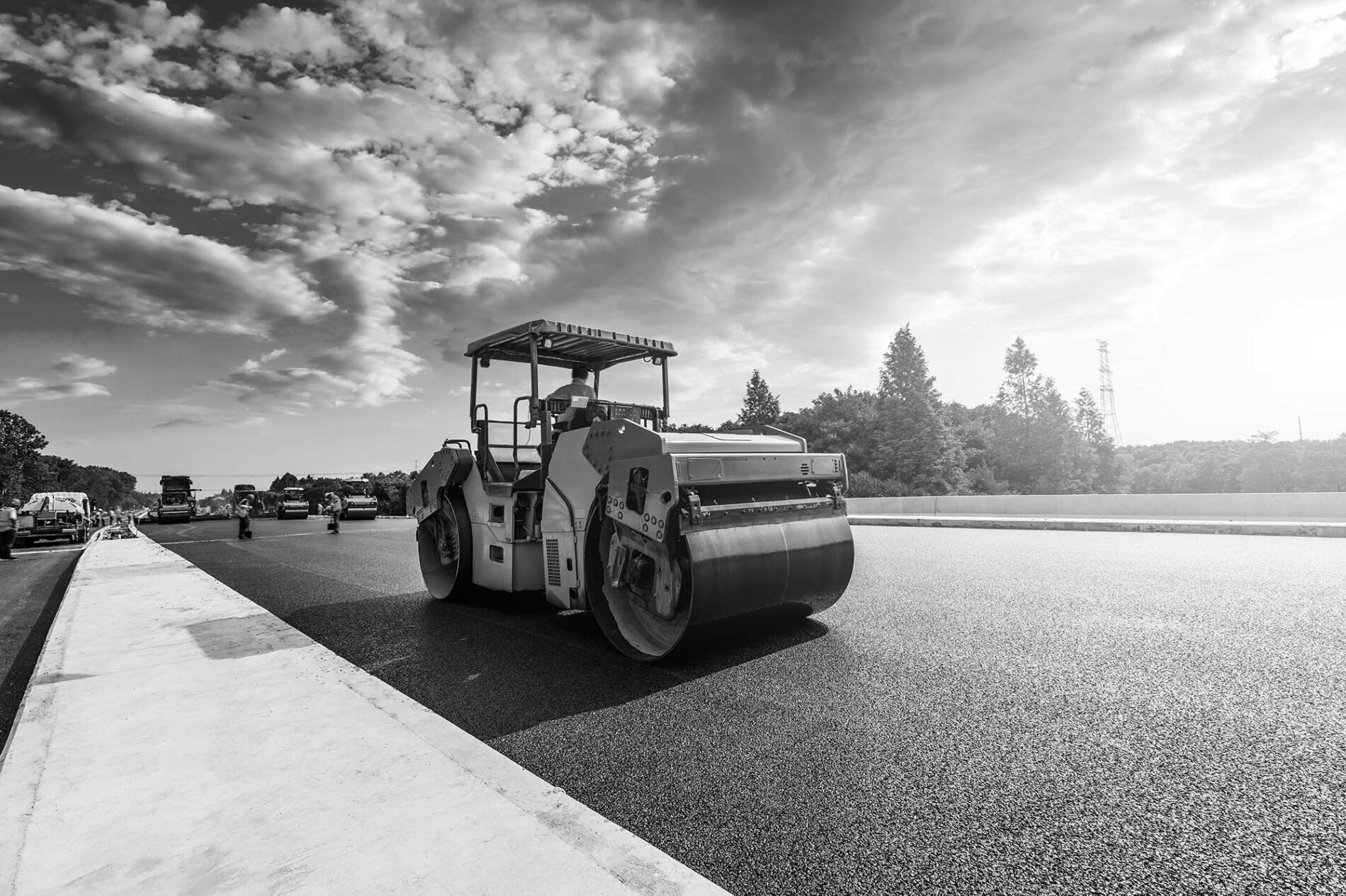 Construction site is laying new asphalt pavement, road construction workers and road construction machinery scene. Highway construction site scene.